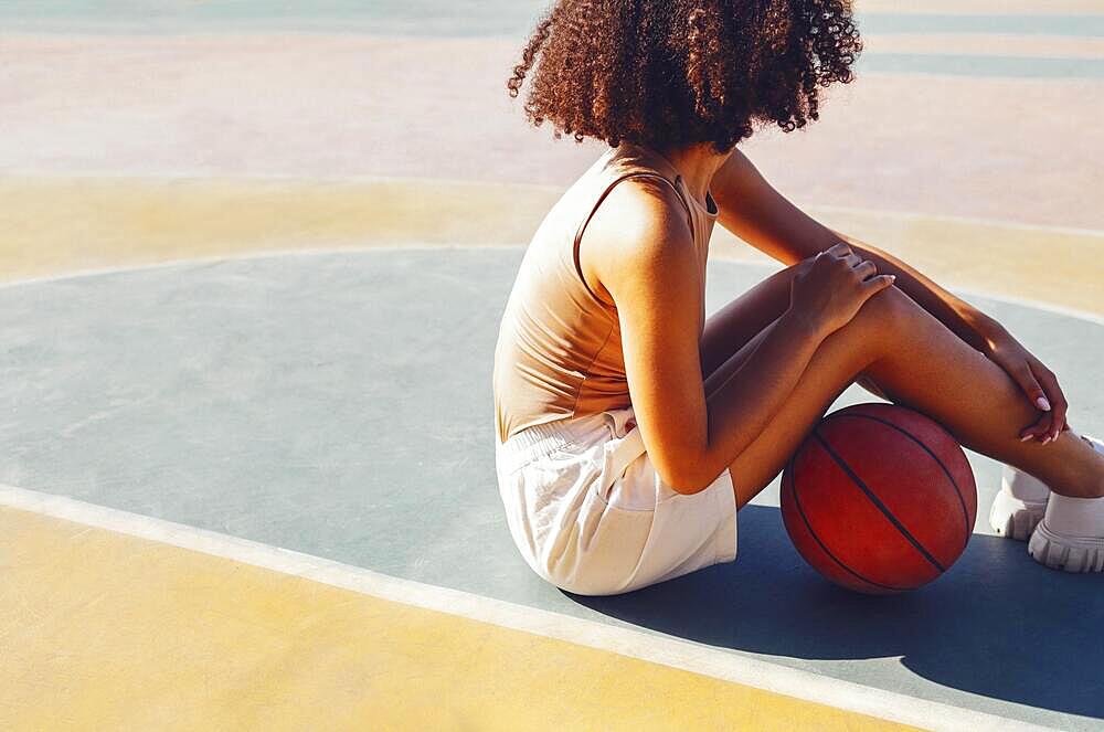 Mixed-race young smiling female outdoors and having fun. Stylish cool teen girl gathering at basketball court, playing basketball outdoors