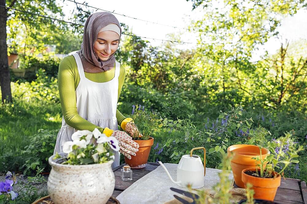 Muslim young attractive gardener at work, take care of green plants, working in retro garden shop