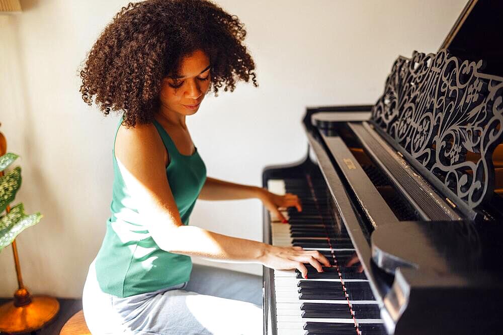 Young black lady playing a piano. Happy smiling woman enjoy fun learning to play piano music instrument