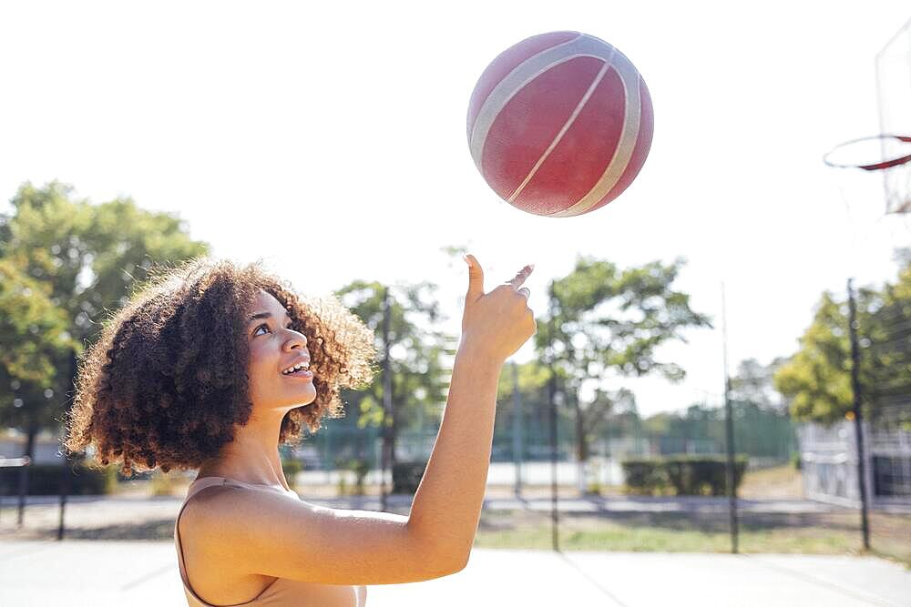 Mixed-race young smiling female outdoors and having fun. Stylish cool teen girl gathering at basketball court, playing basketball outdoors