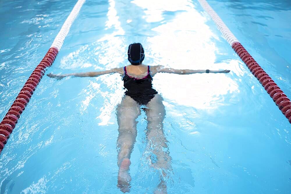 Portrait of a fit woman catcher in the pool. Portrait of a competitive female catcher near the use. Young swimmer wears a swim cap and puts away goggles