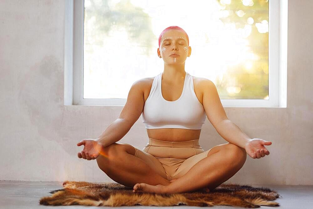 Happy young caucasian bald woman in light sunny room. Beautiful excited female model. Human emotions, facial expression concept. Keep calm, doing yoga