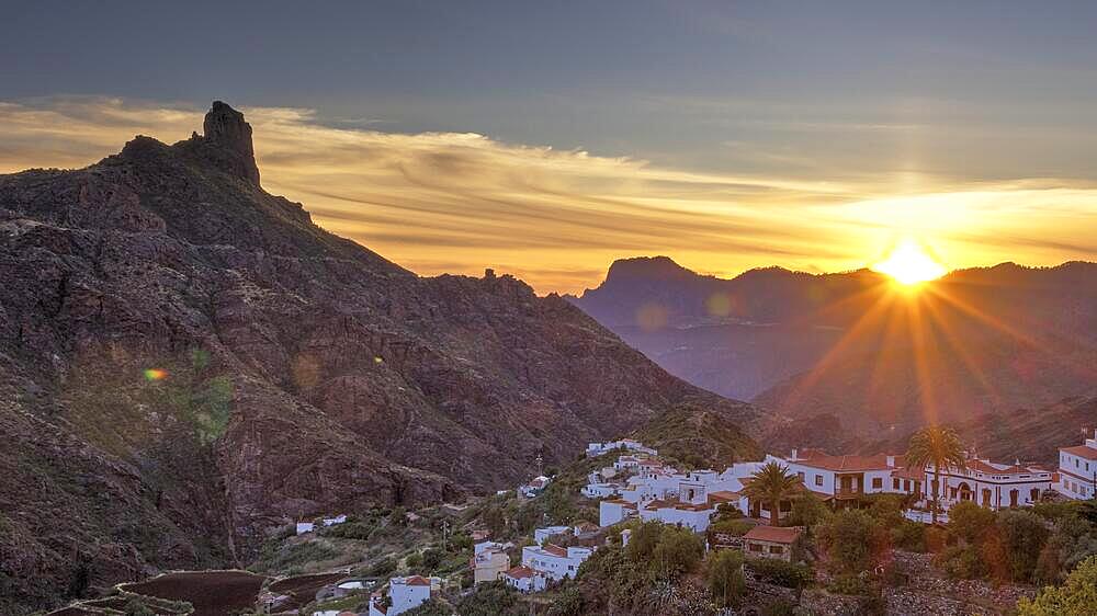 Dusk, sunset, sun as star, Tejeda, village, white houses, red roofs, Massif Central, Roque Bentayga, mountain landscape, blue sky, orange clouds, grey clouds, Gran Canaria, Canary Islands, Spain, Europe