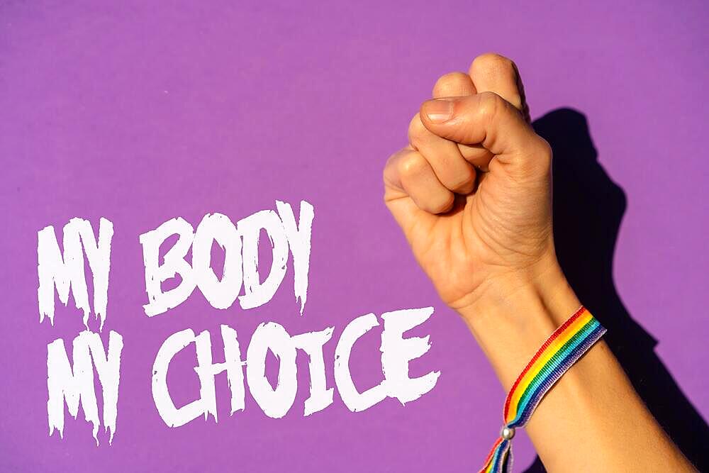 A woman with her fist raised and a text in favor of the legalization of abortion. Protest not to make abortion illegal in the united states, pro-choice, pro-life, on a purple background