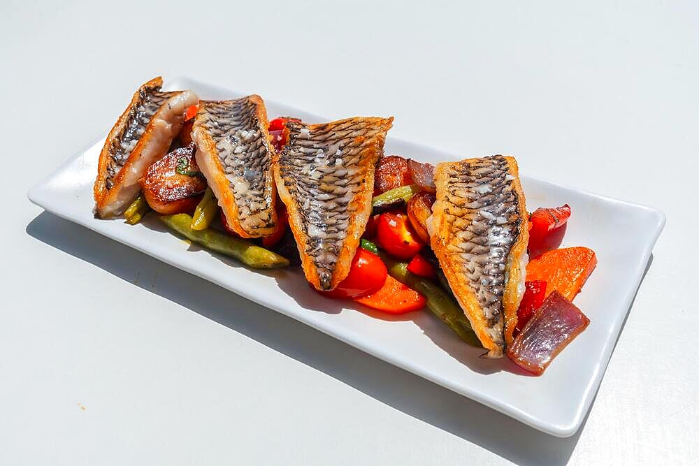 Fried fish with vegetables on a white tray, traditional Mediterranean food