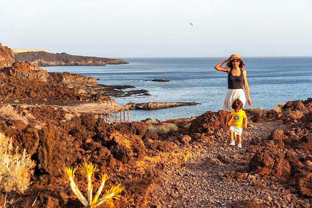 Mother and son walking on a path at sunset on Tacoron beach on El Hierro, Canary Islands