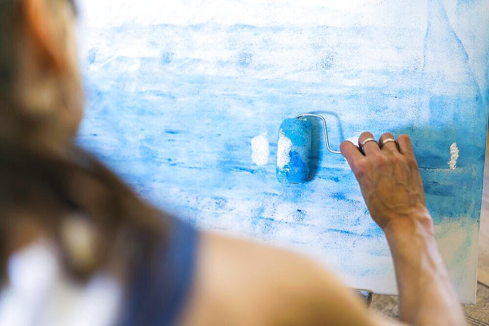 Close up of a woman painting on a canvas a blue abstract painting