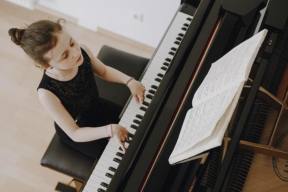 Elegant girl sits at the concert grand and plays the piano