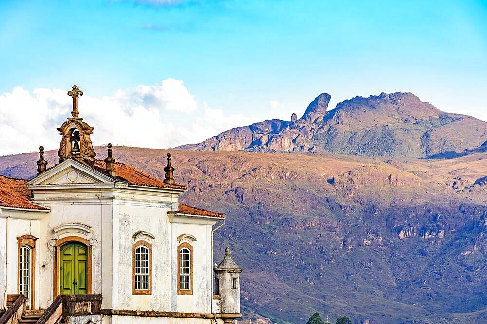 Antique baroque church in the city of Ouro Preto in Minas Gerais with the mountains and peak of Itacolomi in the background during sunset