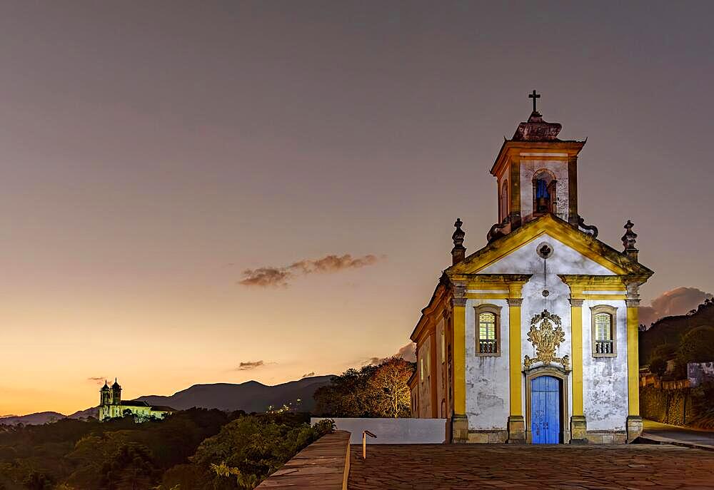 Image with illuminated baroque style churches on top of the hill in Ouro Preto, Minas Gerais illuminated during dusk