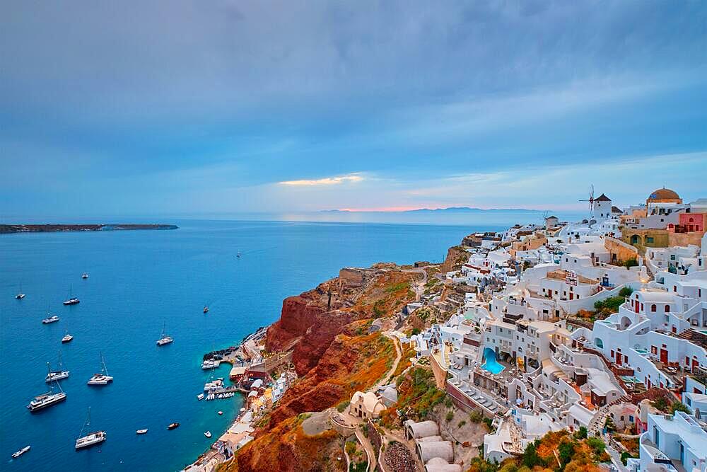 Famous greek iconic selfie spot tourist destination Oia village with traditional white houses and windmills in Santorini island at sunset in twilight, Greece, Europe