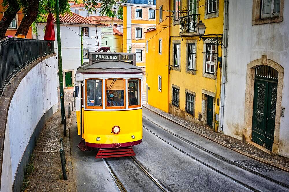 Famous vintage yellow tram 28 in the narrow streets of Alfama district in Lisbon, Portugal, symbol of Lisbon, famous popular travel destination and tourist attraction, Europe