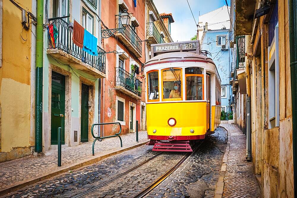 Famous vintage yellow tram 28 in the narrow streets of Alfama district in Lisbon, Portugal, symbol of Lisbon, famous popular travel destination and tourist attraction, Europe