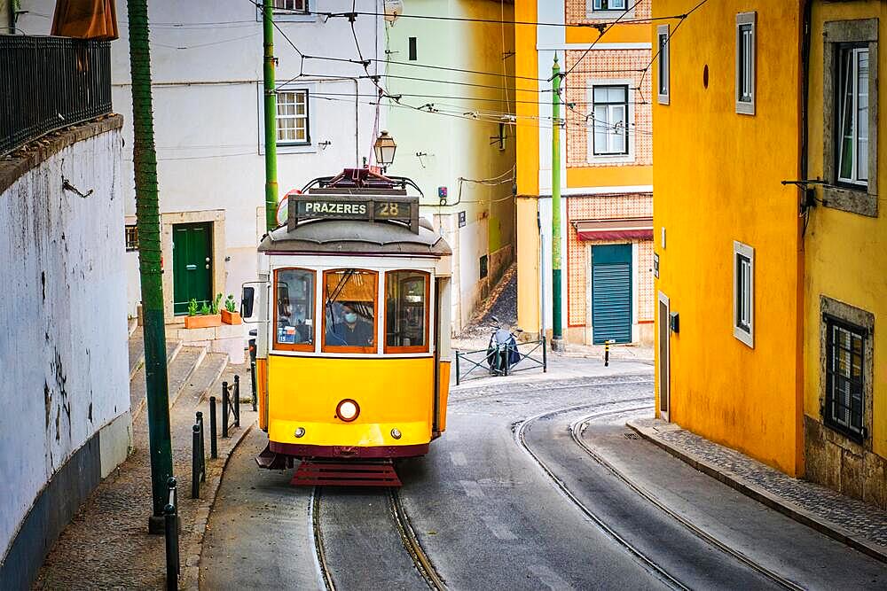 Famous vintage yellow tram 28 in the narrow streets of Alfama district in Lisbon, Portugal, symbol of Lisbon, famous popular travel destination and tourist attraction, Europe