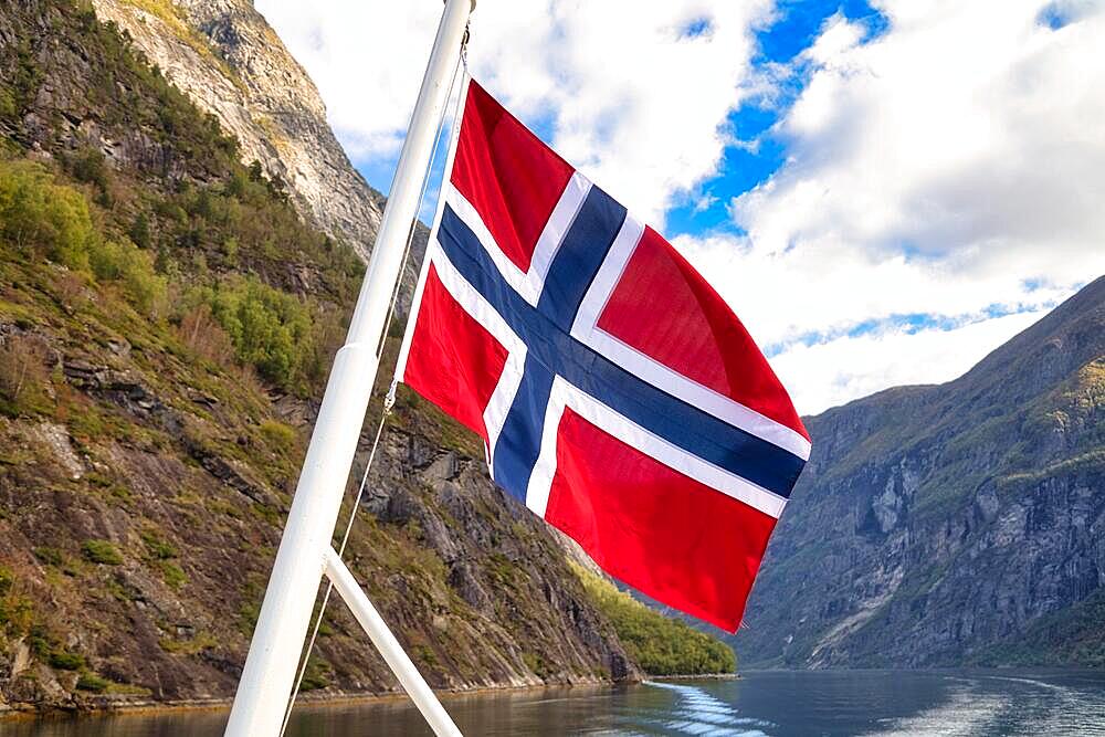 Norwegian flag in front of mountain panorama in Geirangerfjord near Geiranger, UNESCO World Heritage Site, Norway, Europe