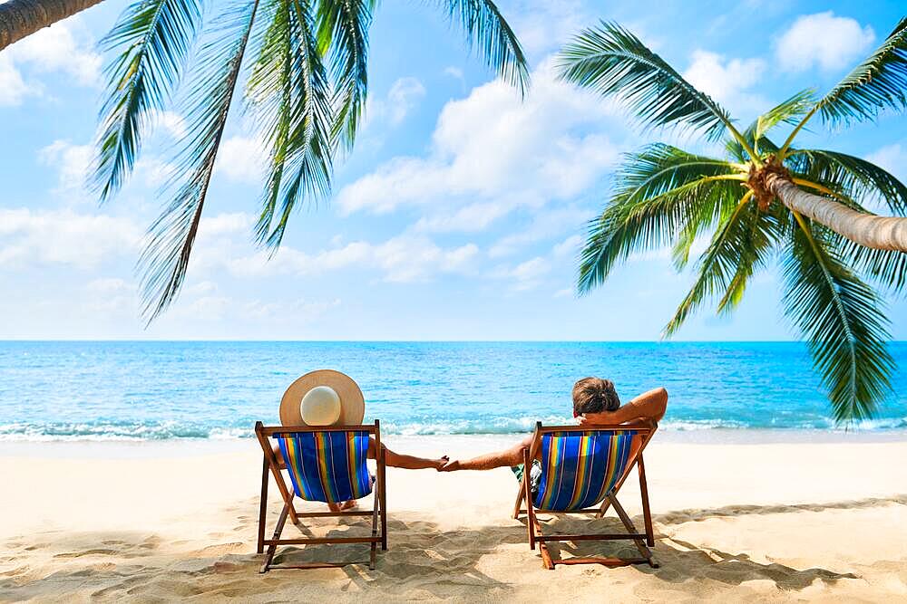 Couple relax on the beach enjoying beautiful sea on the tropical island. Summer beach vacation concept