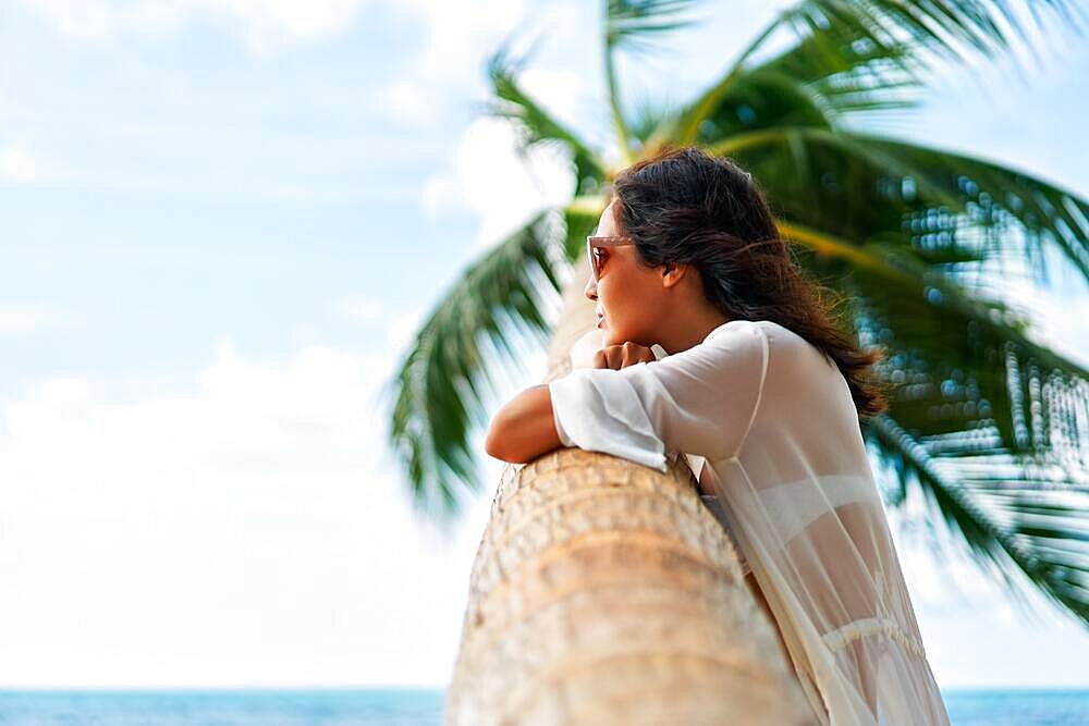 Dreaming beautiful woman relax on tropical beach with palm tree. Carefree concept