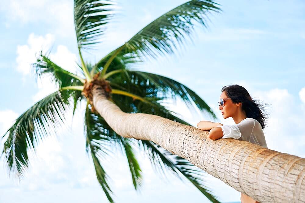 Dreaming beautiful woman relax on tropical beach with palm tree. Carefree concept