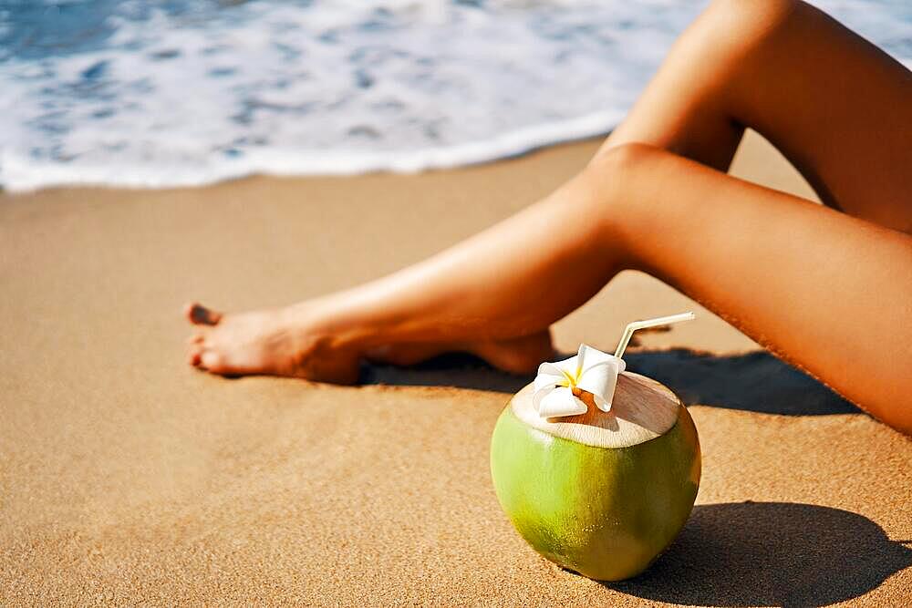 Beautiful woman relax on tropical sandy beach with coconut. Vacation concept, summer background