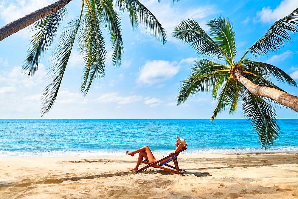 Young beautiful woman sunbathe and relax on tropical beach. Summer vacation concept