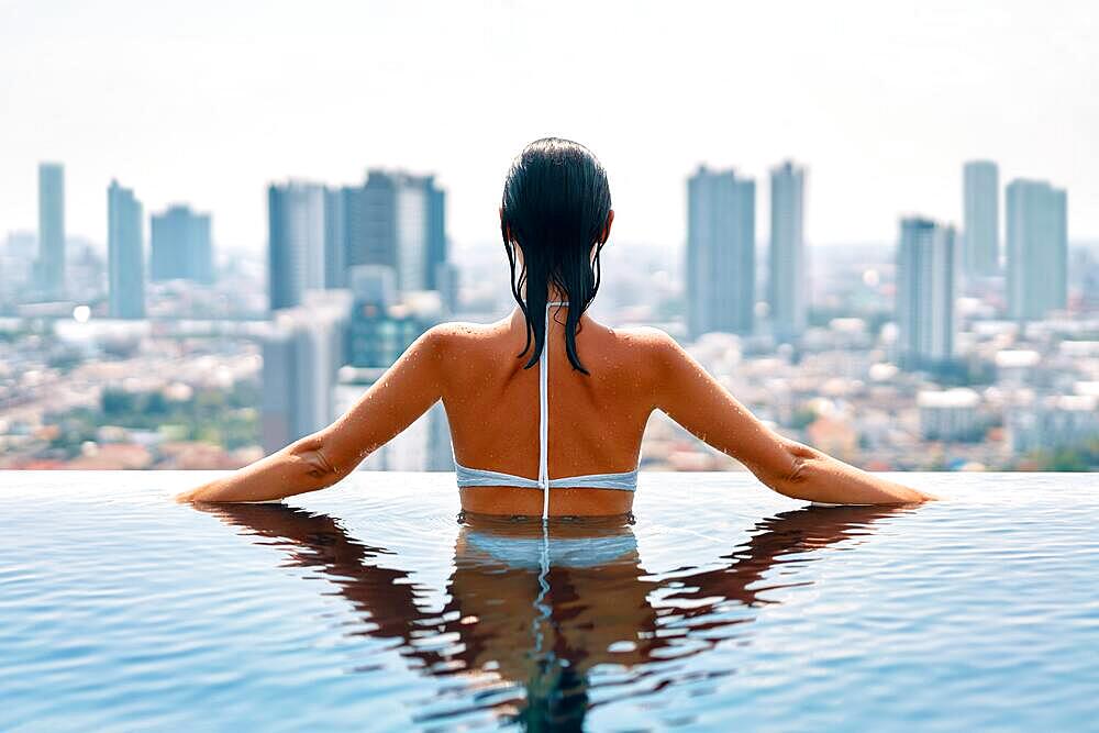 Back view of slim beautiful woman relax in swimming pool. Summer vacation concept