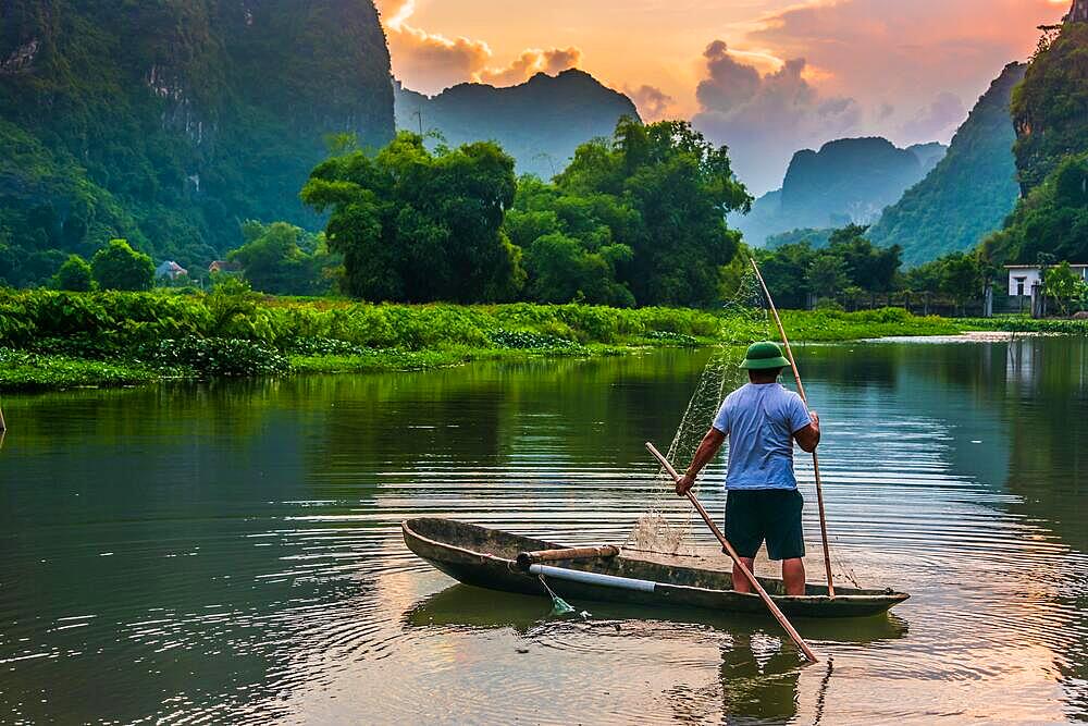 Fisherman on boat in Trang An, a scenic area near Ninh Binh, Vietnam inscribed as a UNESCO World Heritage Site in 2014