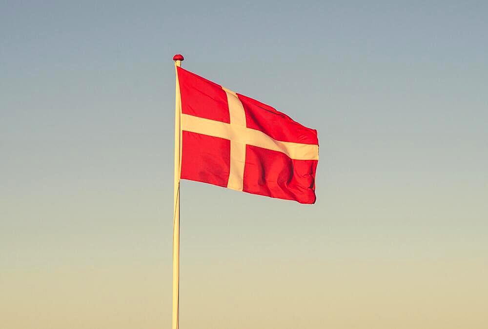 Danish flag at dawn waving in the wind in the sunset on a sunny evening