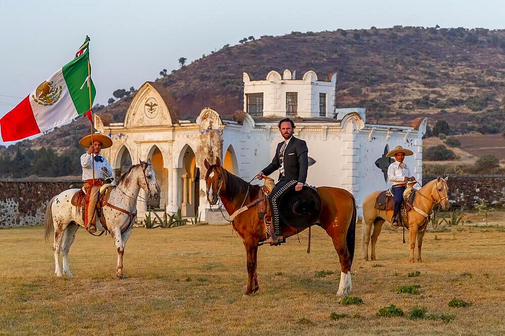 A handsome Mexican Charro poses in front of a hacienda in the Mexican countryside