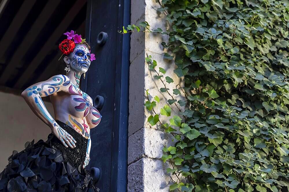 A gorgeous Hispanic Brunette model poses with traditional skull sugar makeup paint for a Mexican festival