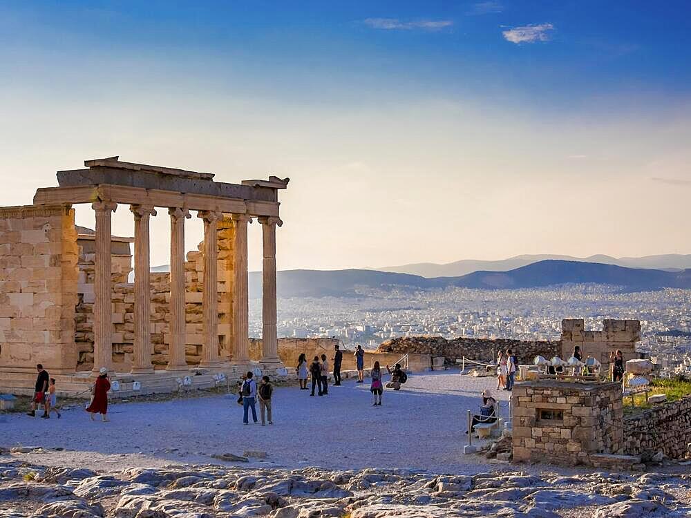 View of Erechtheion on Acropolis, Athens, Greece, against sunset overlooking the city with tourist taking photos of ruins, Europe