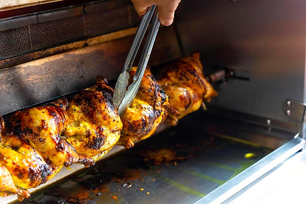 Chef of the kebab restaurant, with a metal tool controlling the chicken grill