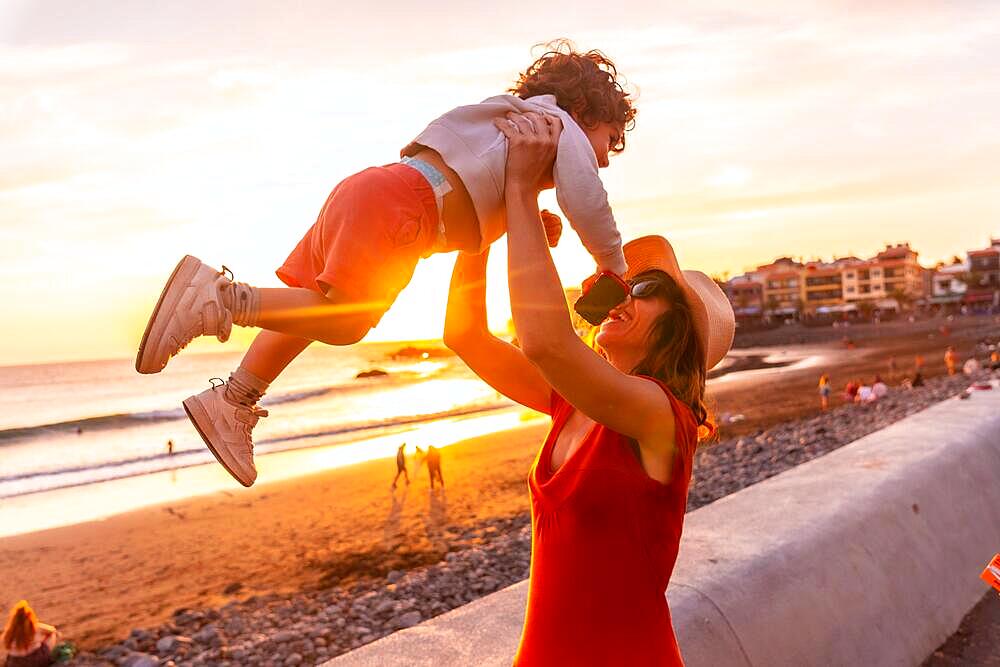 Mother and son at sunset on the beach of Valle Gran Rey in La Gomera, Canary Islands. playing that the child flies