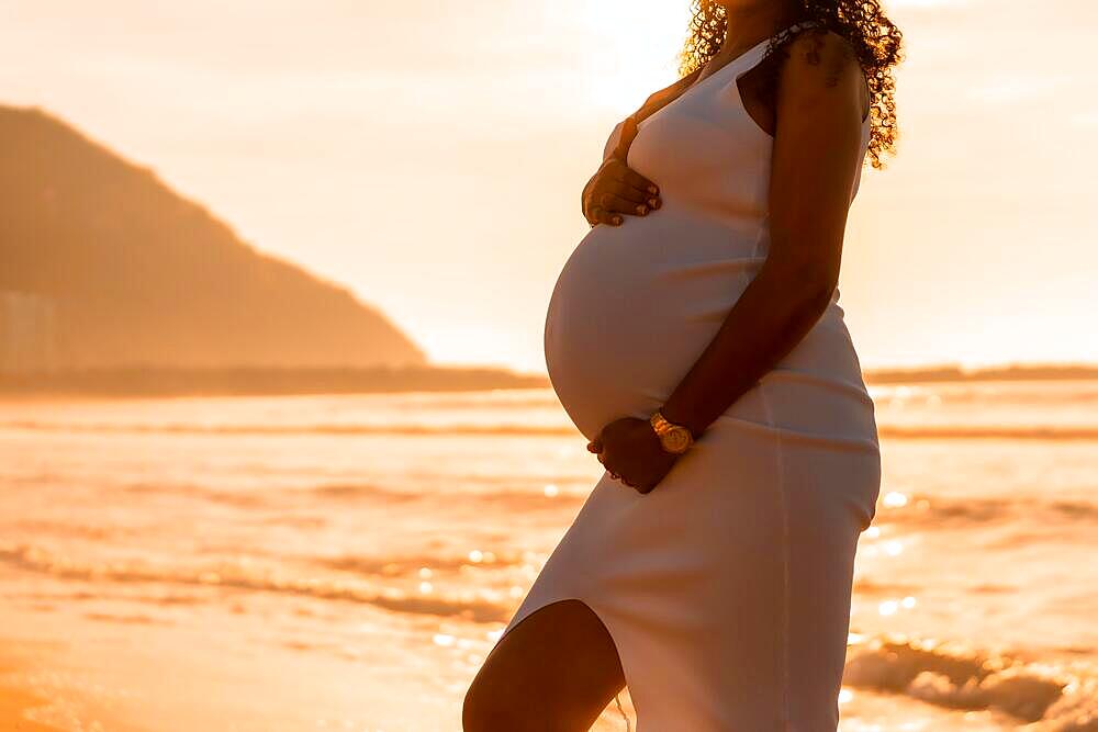 Pregnant maternity latin woman on the beach at sunset, maternity concept. woman silhouette