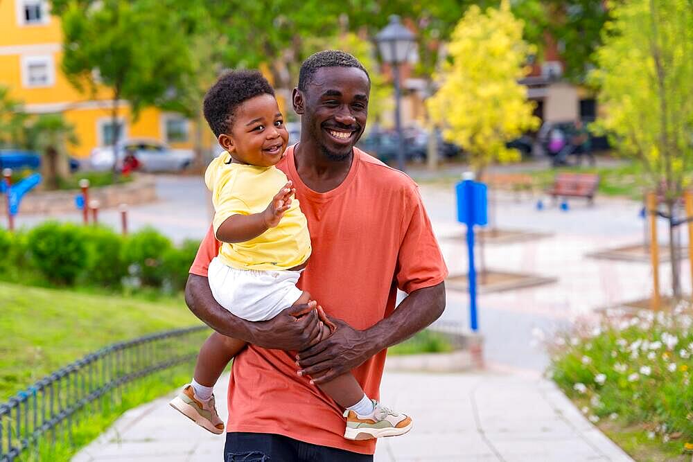 African black ethnicity father having fun with his son in playground