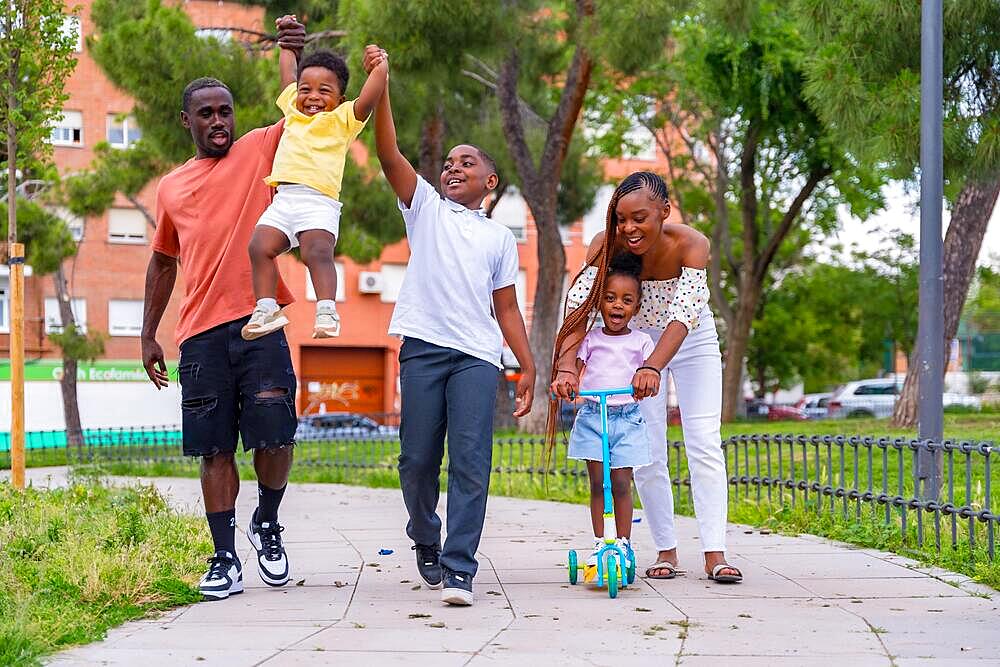 African black ethnicity family with children on playground, having fun and smiling in city park