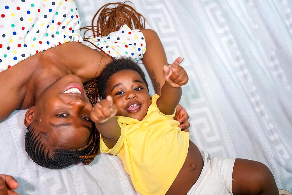 African black ethnic family mother with her little son in bedroom on bed smiling, overhead shot