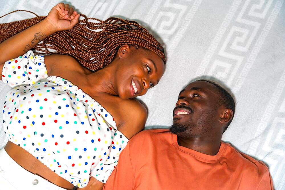 Portrait of black African ethnicity couple in bedroom in bed smiling, overhead shot