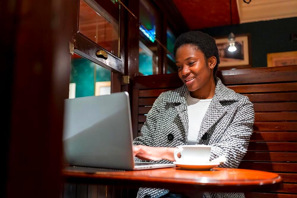 Business woman of African ethnicity in a coffee shop, break time finance woman with a computer