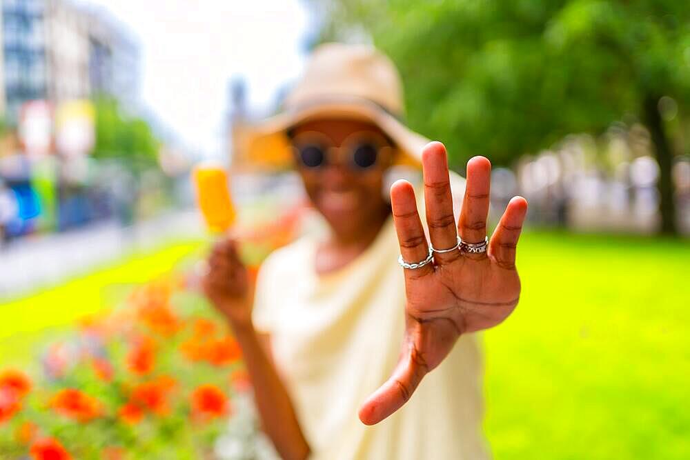 African black ethnicity woman eating a mango ice cream in the city in summer, making stop