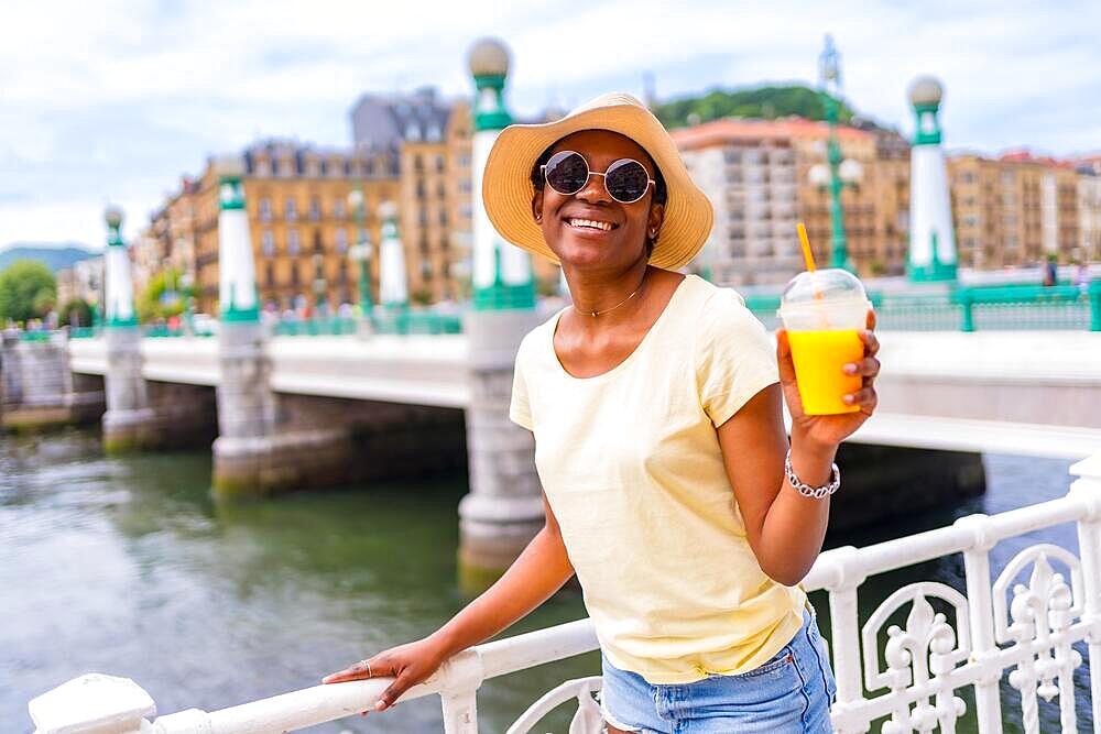 Portrait of black ethnic woman having an orange juice enjoying summer on vacation