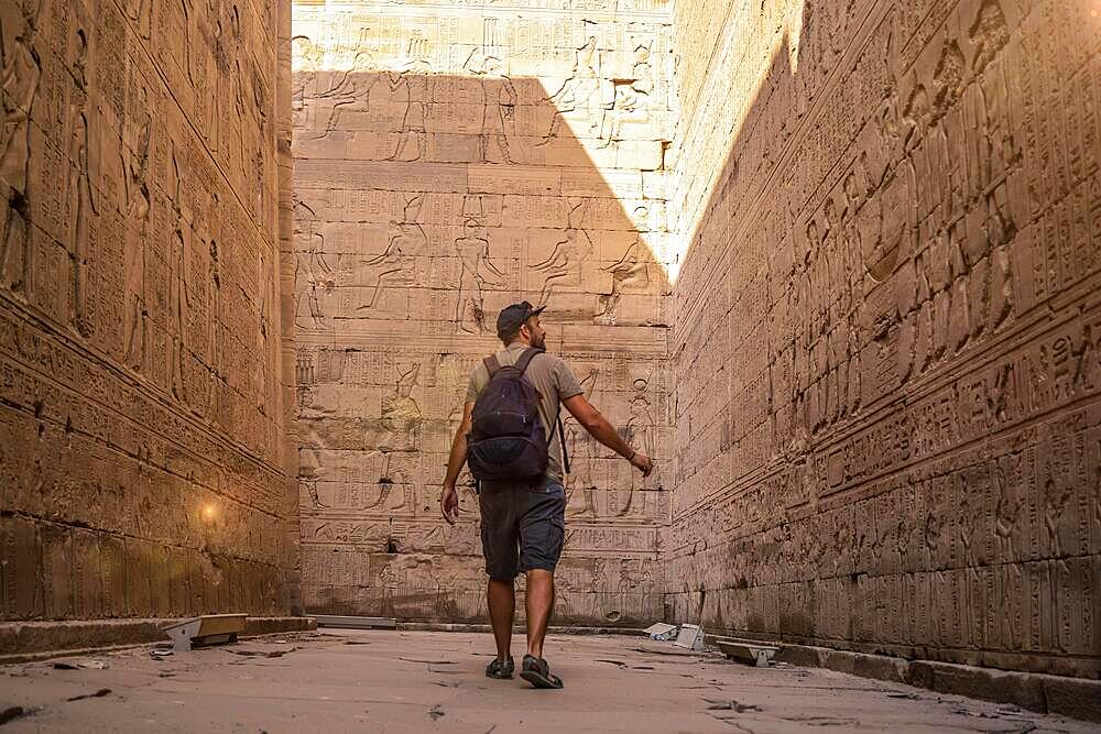 A young tourist visiting the beautiful temple of Edfu in the city of Edfu, Egypt. On the bank of the Nile river, geco-Roman construction, temple dedicated to Huros