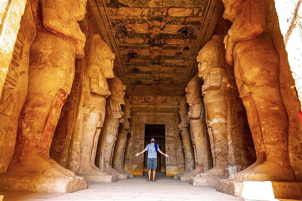 A young tourist looking at the pharaohs at the Abu Simbel Temple in southern Egypt in Nubia along Lake Nasser. Temple of Pharaoh Ramses II, travel lifestyle