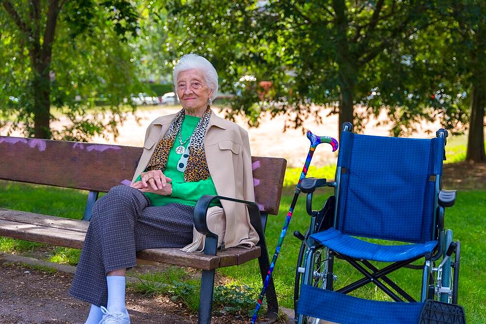 Portrait of an elderly woman sitting on a chair in the garden of a nursing home in a wheelchair