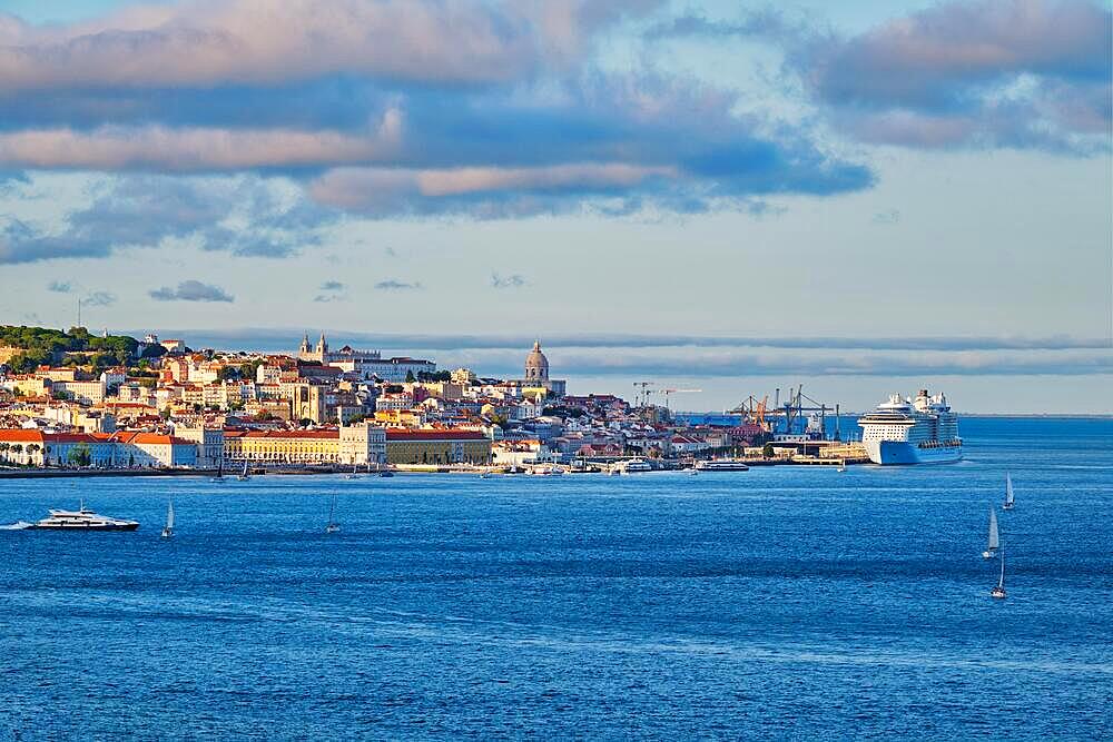 View of Lisbon over Tagus river from Almada with yachts tourist boats and passenger ferry and moored cruise liner on sunset with dramatic sky. Lisbon, Portugal, Europe