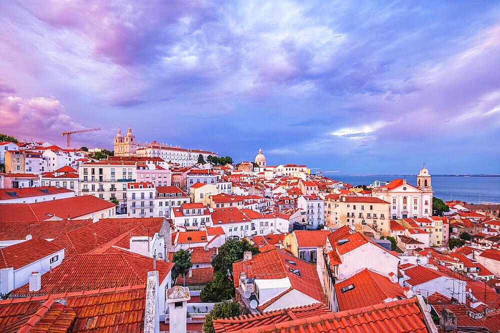 View of Lisbon famous view from Miradouro de Santa Luzia tourist viewpoint over Alfama old city district on sunset with dramatic overcast sky. Lisbon, Portugal, Europe