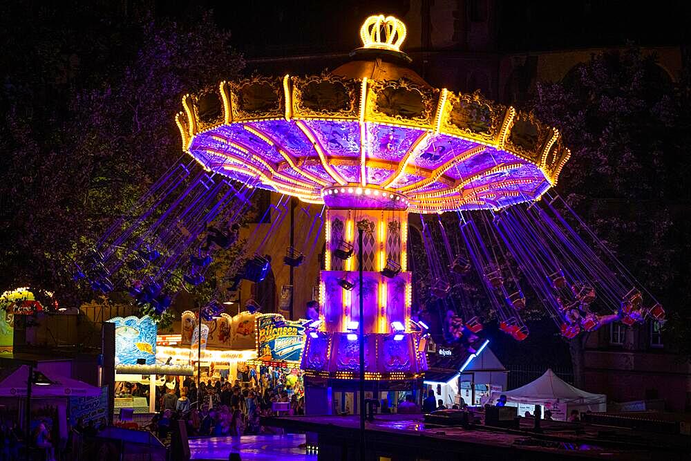 The colourful lights of the carousel at the Mainfest glow in the evening. The Mainfest on the Mainkai, Fahrtor and Roemerberg is one of Frankfurt's oldest public festivals. The official opening takes place in 2023 on 04 August at 6 p.m. at the Gerechtigkeitsbrunnen on Roemerberg. The festival ends with a big fireworks display over the Main on Monday, 07.08.2023., Mainufer, Frankfurt am Main, Hesse, Germany, Europe