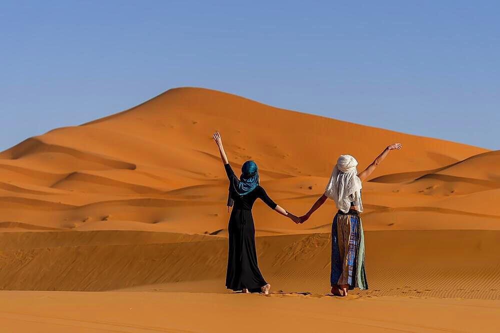 A beautiful model poses against the sand dunes in the great Sahara desert in Morocco