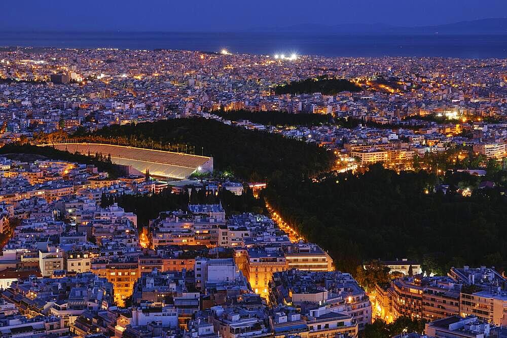 Night view of Athens, Greece with ancient and restored Panathenaic stadium of Kallimarmaro, shot form hill of Lycabettus. Beautiful city at blue hour, iconic site for Olympic games movement. National Garden in center of city