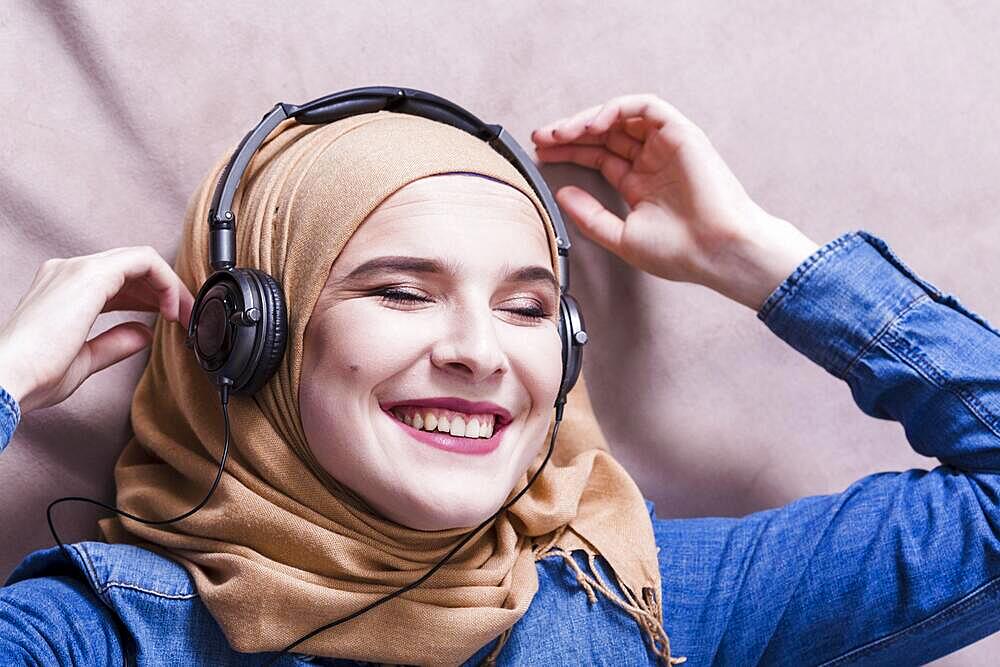 Muslim woman listening music headphones