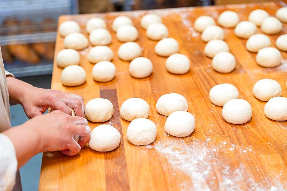 Hands of female baker in the bakery workshop of artisan bakery preparing the bread dough